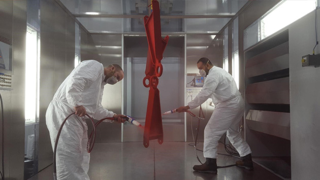 two men powder coating a piece of equipment