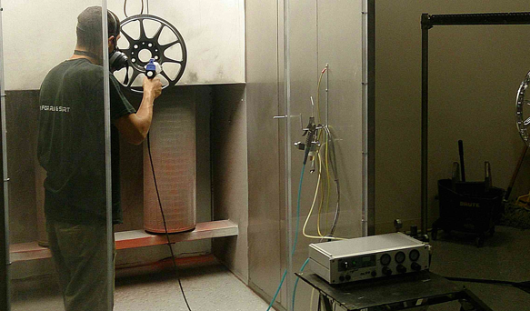 a man powder coats the rim of a wheel